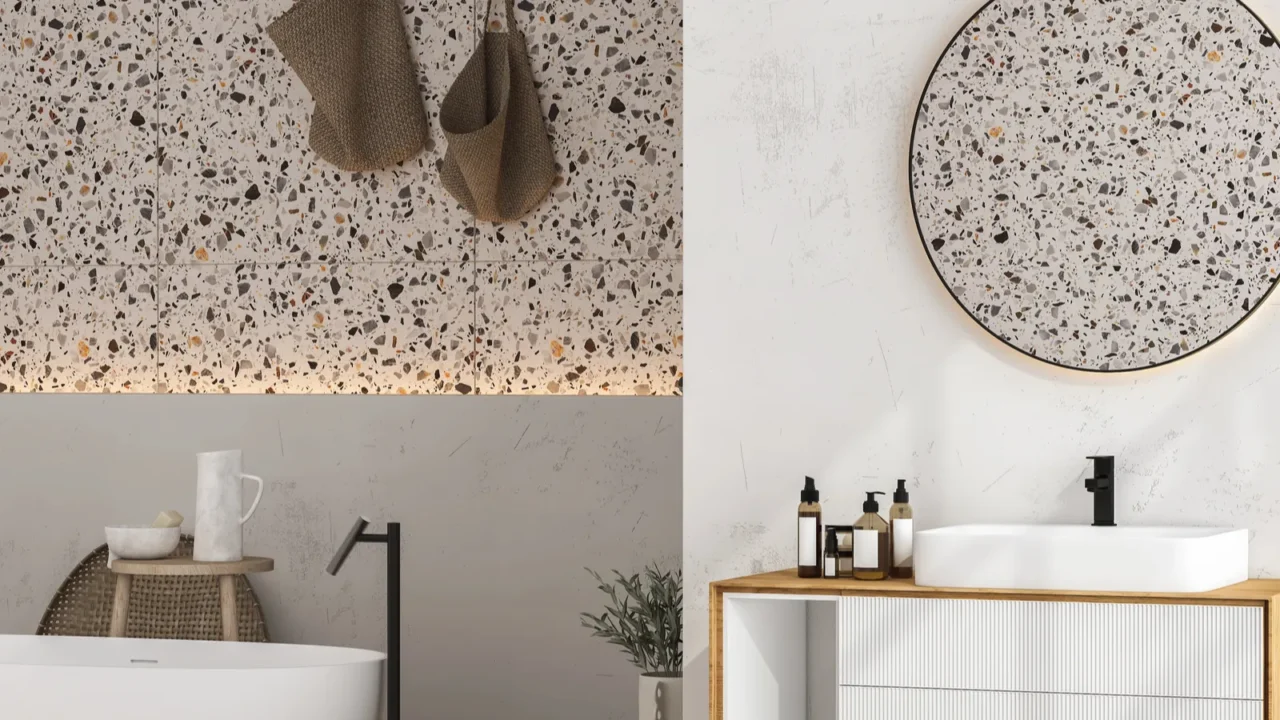 A modern bathroom with a terrazzo wall, white sink and a sleek white tub.