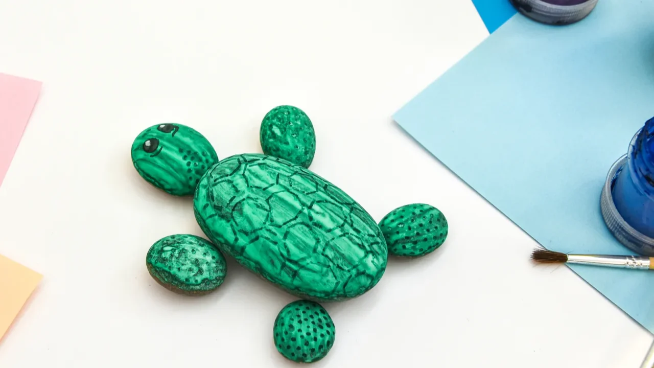 A DIY painted rock turtle on a white surface.