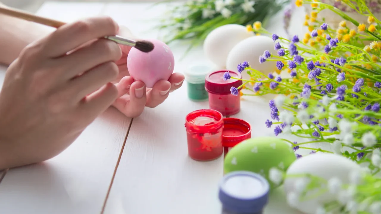 A person painting eggs placed on a white table.