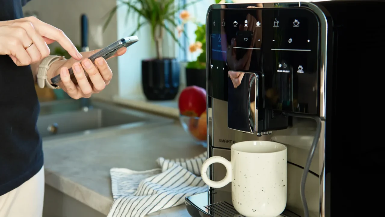 person uses smartphone app to operate coffee machine woman preparing