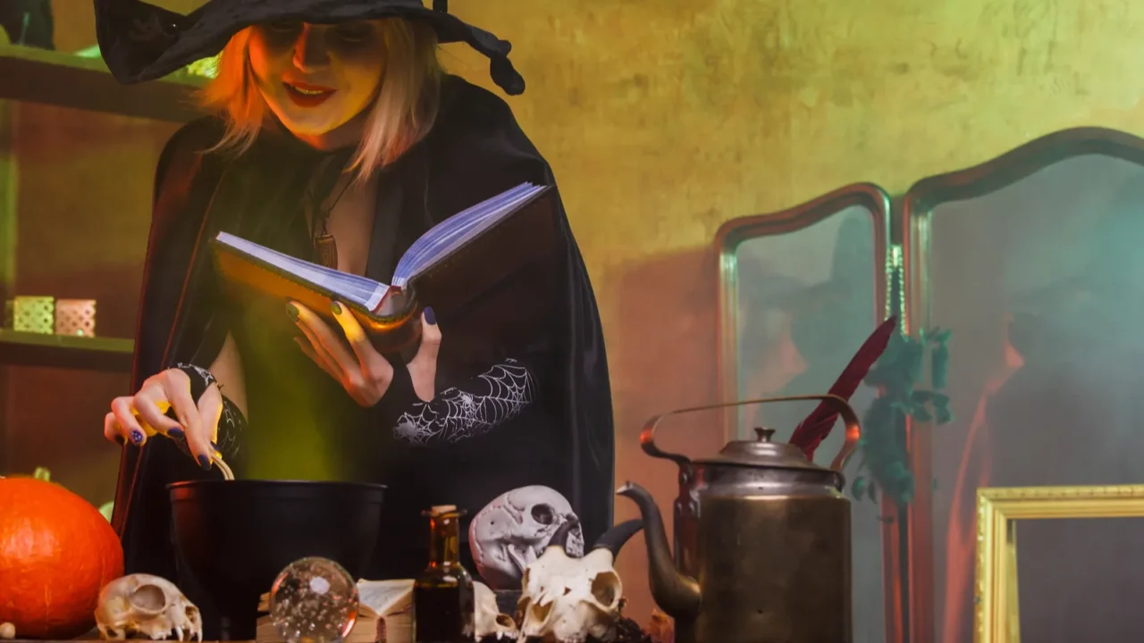 photo of witch in black hat reading spell over pot