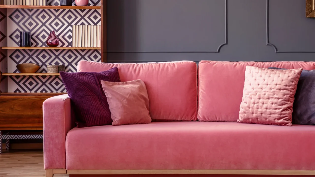 pink velvet couch with decorative pillows standing in grey living