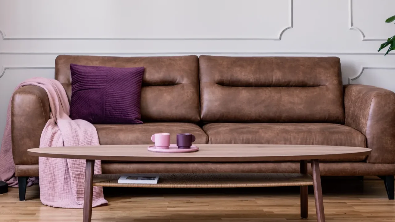 purple pillow and pastel pink blanket placed on leather couch