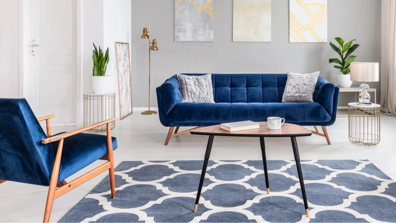 A stylish living room with a blue sofa, artwork, and decorative plants.