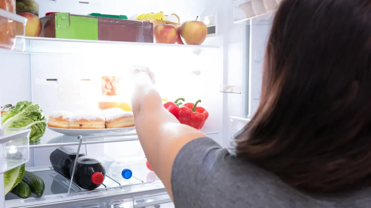 rear view of a young woman taking food from refrigerator