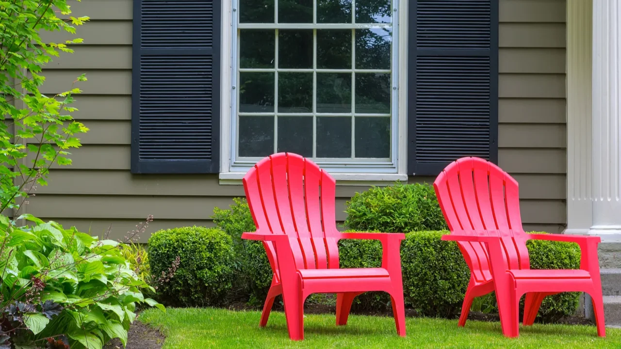 red outdoor patio chairs on green grass lawn of house