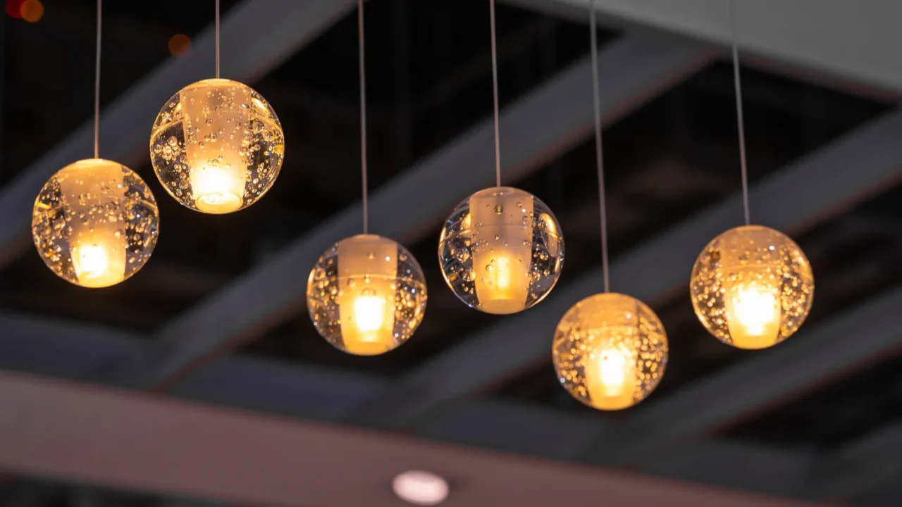 A dining area with a chandelier and string lights against a light wall.