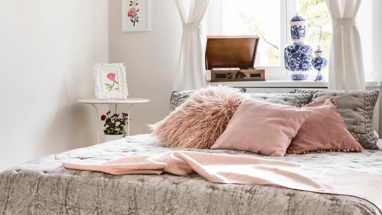 A stylish and inviting bedroom area showcasing decorative pillows, tranquil colors, and natural light filtering through the window.