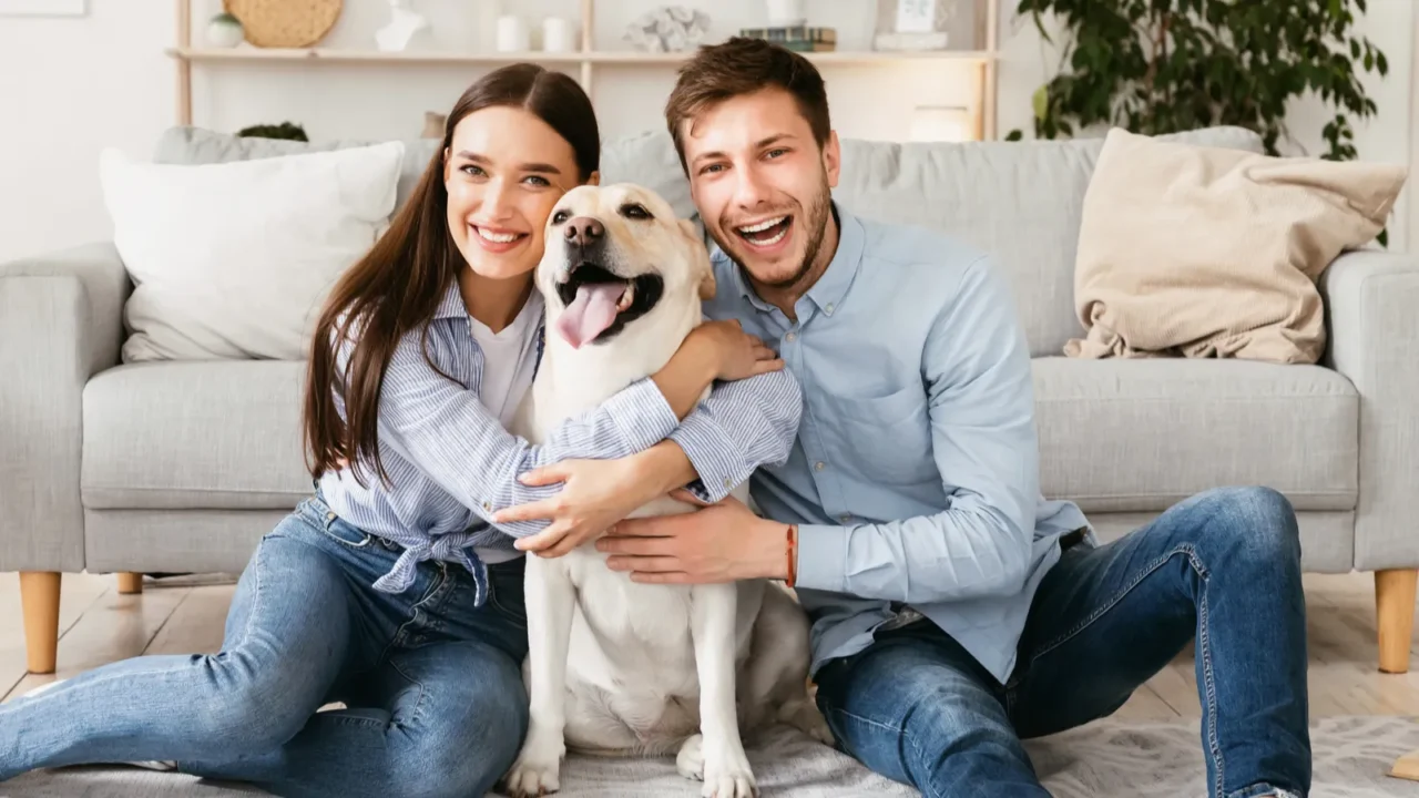 young happy couple with dog sitting on floor