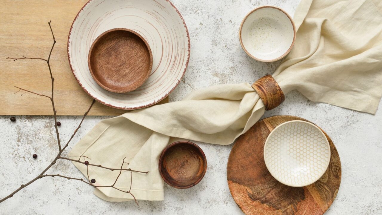 An array of various bowls and a linen fabric tied in a stylish manner on a textured background.