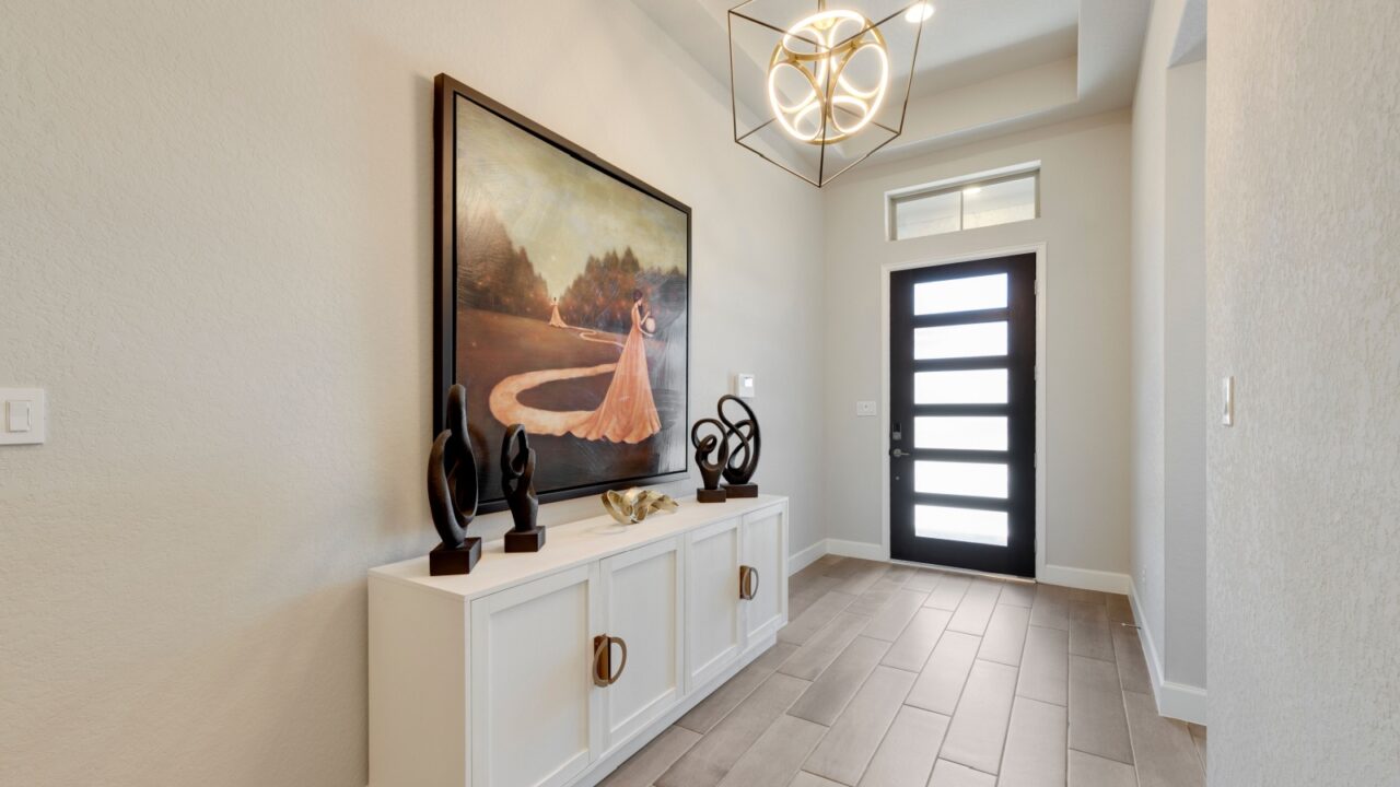 An entryway featuring a white console table with an artwork on wall and a black door.