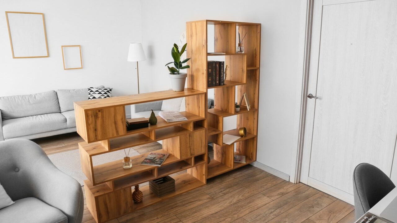 Modern living room with wooden bookshelf, gray sofa, and white floor lamp.