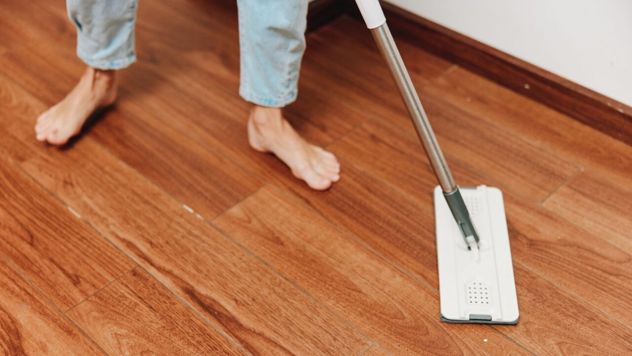 A person cleaning a hardwood floor with a mop.