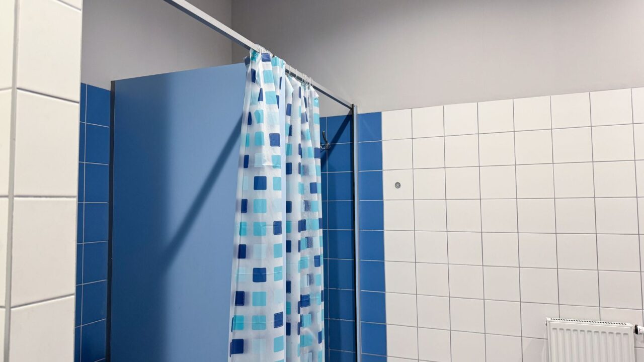 A bathroom interior with blue and white tiles and a patterned shower curtain.