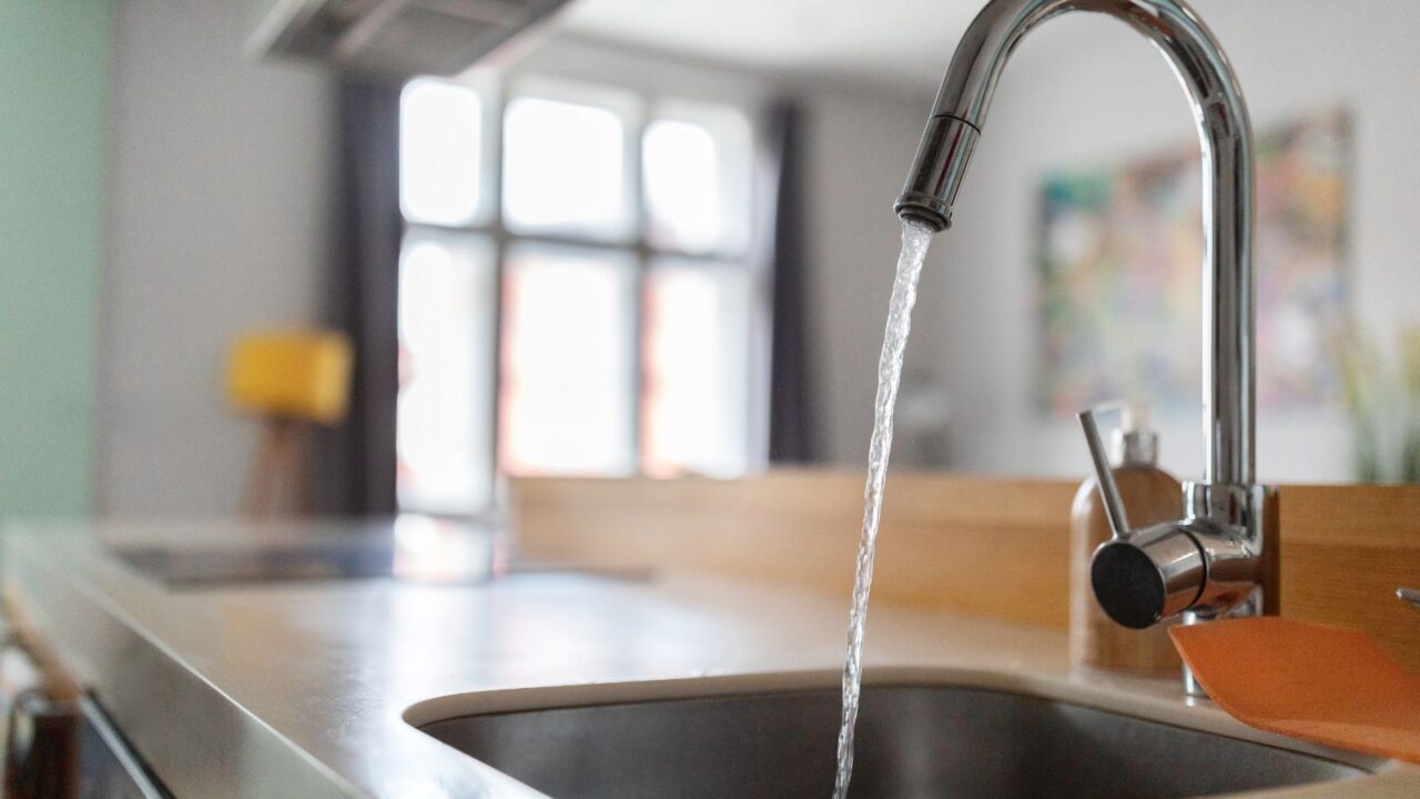 Water flowing from a chrome faucet into the sink.