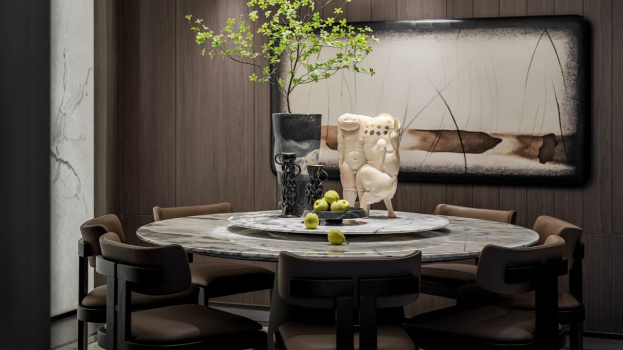 A stylish dining room interior with a marble top dining table, chairs, plant vase, and a sculpture on the table.