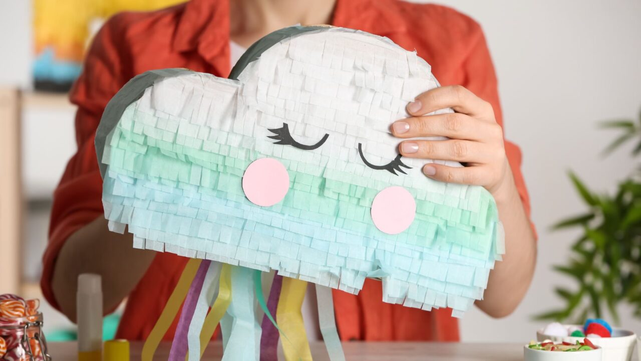 A woman making a pinata with cardboard and paper ribbons.