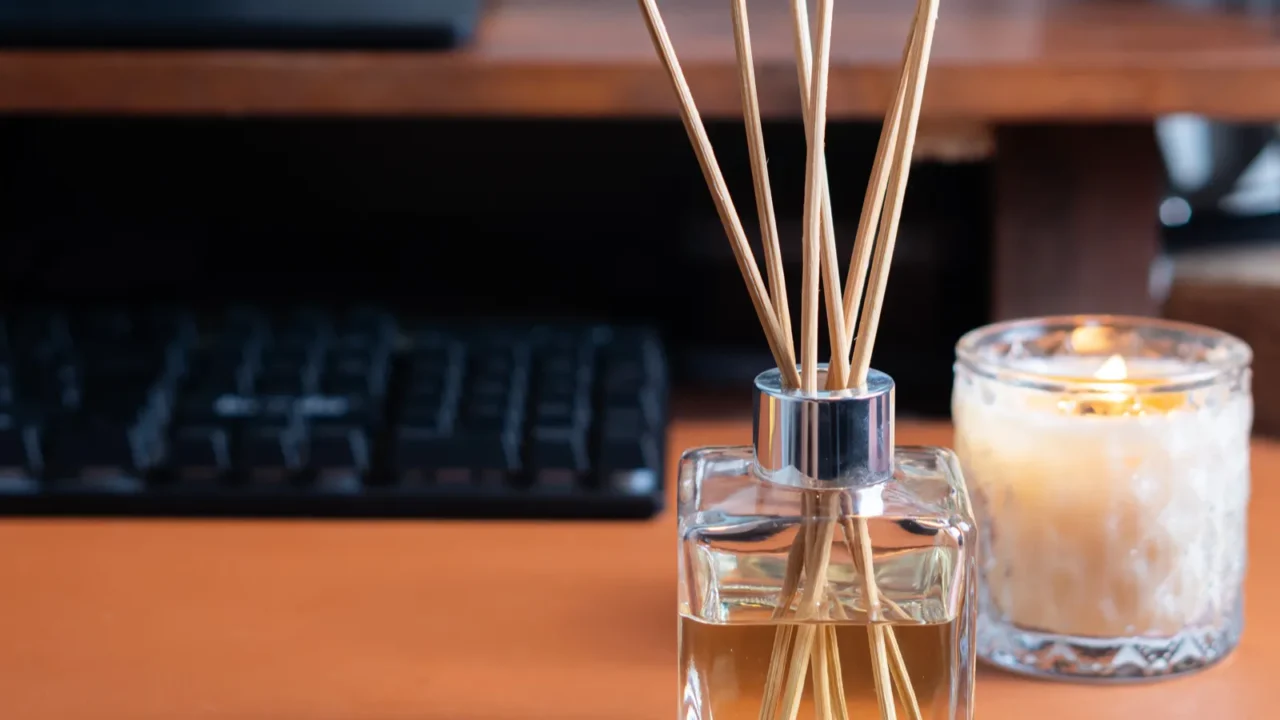 a stylish glass diffuser with wooden reeds sits on a