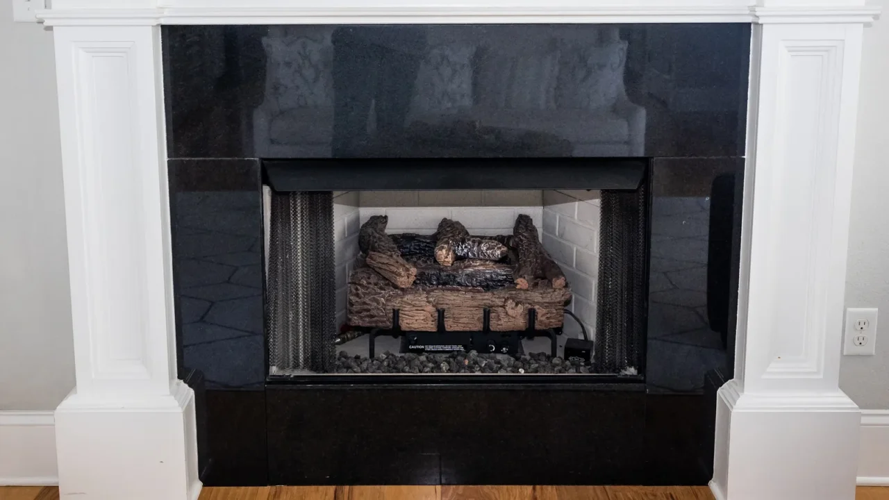 a white detailed ornate wood mantle with a gas fireplace