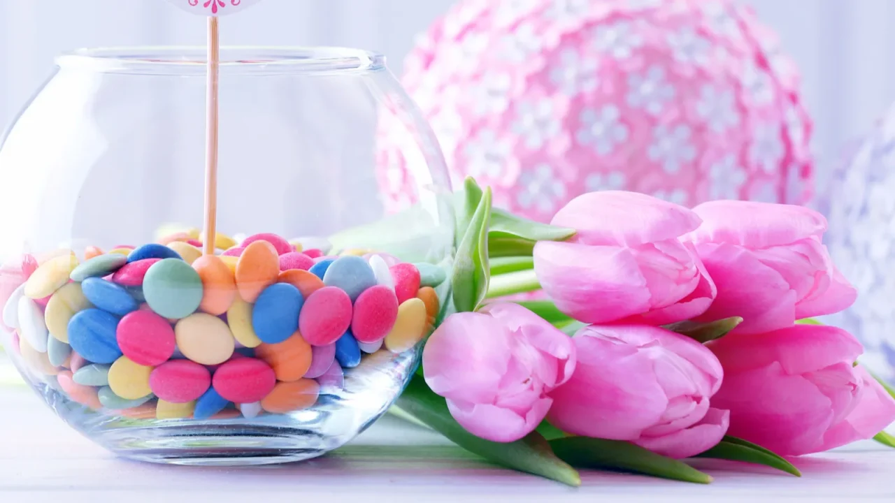 beautiful pink tulips with sweets in vase on table on