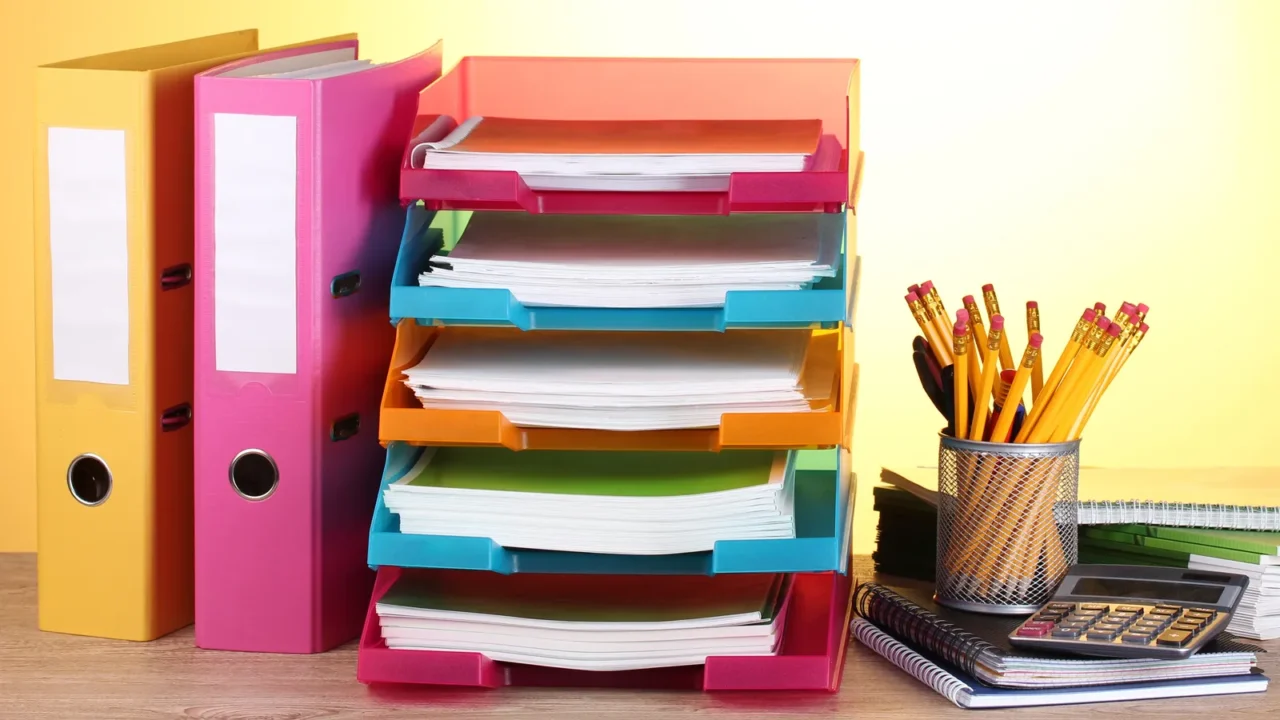 bright paper trays and stationery on wooden table on yellow