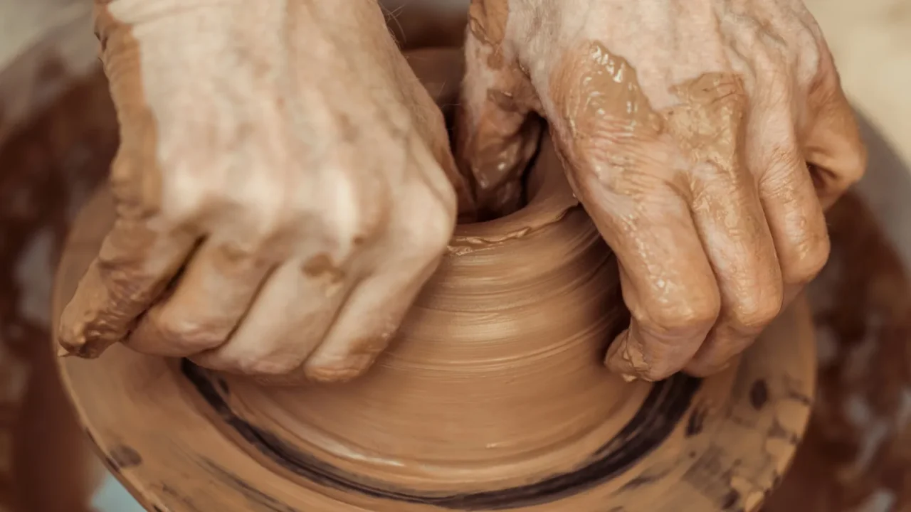 A person molding clay on a spinning pottery wheel.