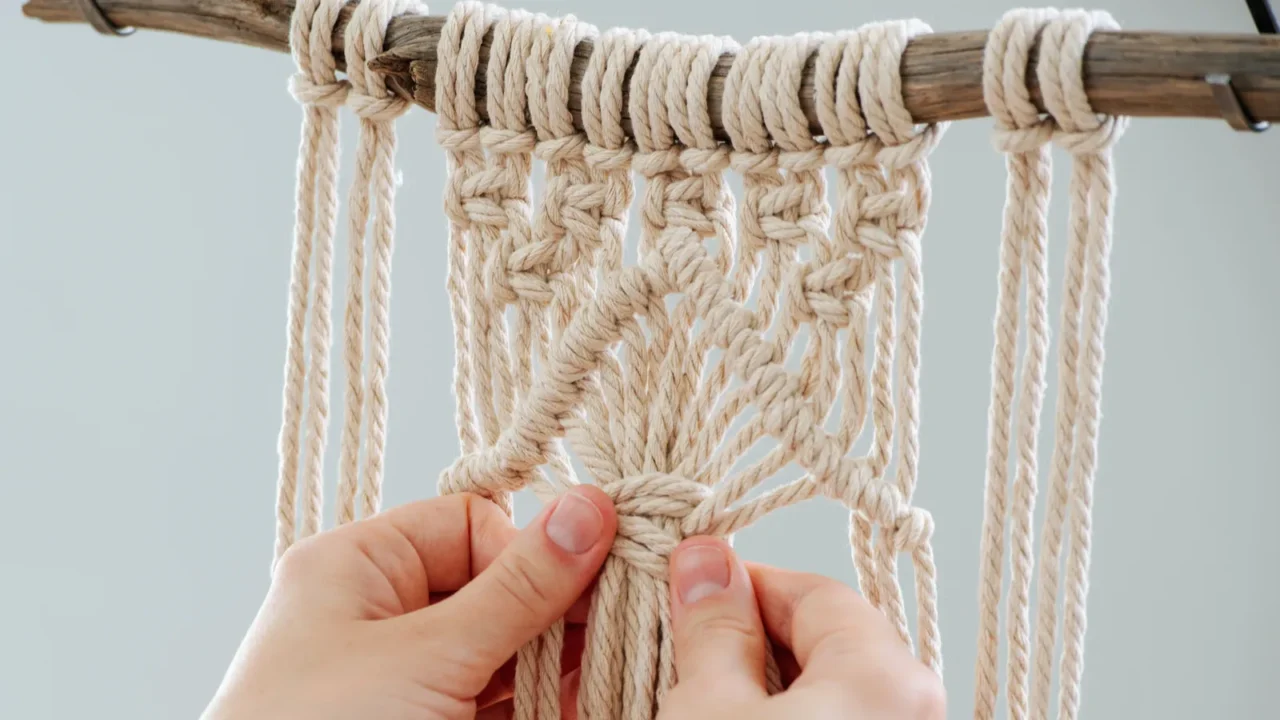 craftswoman weving ropes creating a macrame banner from behind