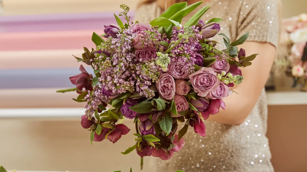 cropped view of florist making bouquet of purple tulips peonies