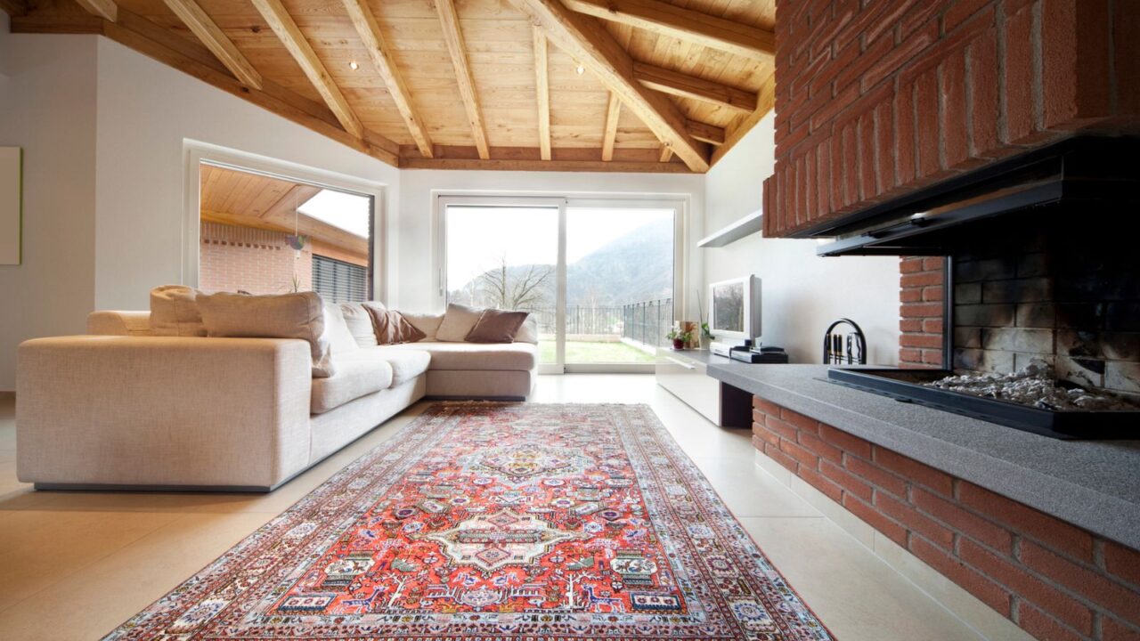 A cozy living room with a beige sofa and a colorful rug beneath a wooden ceiling.