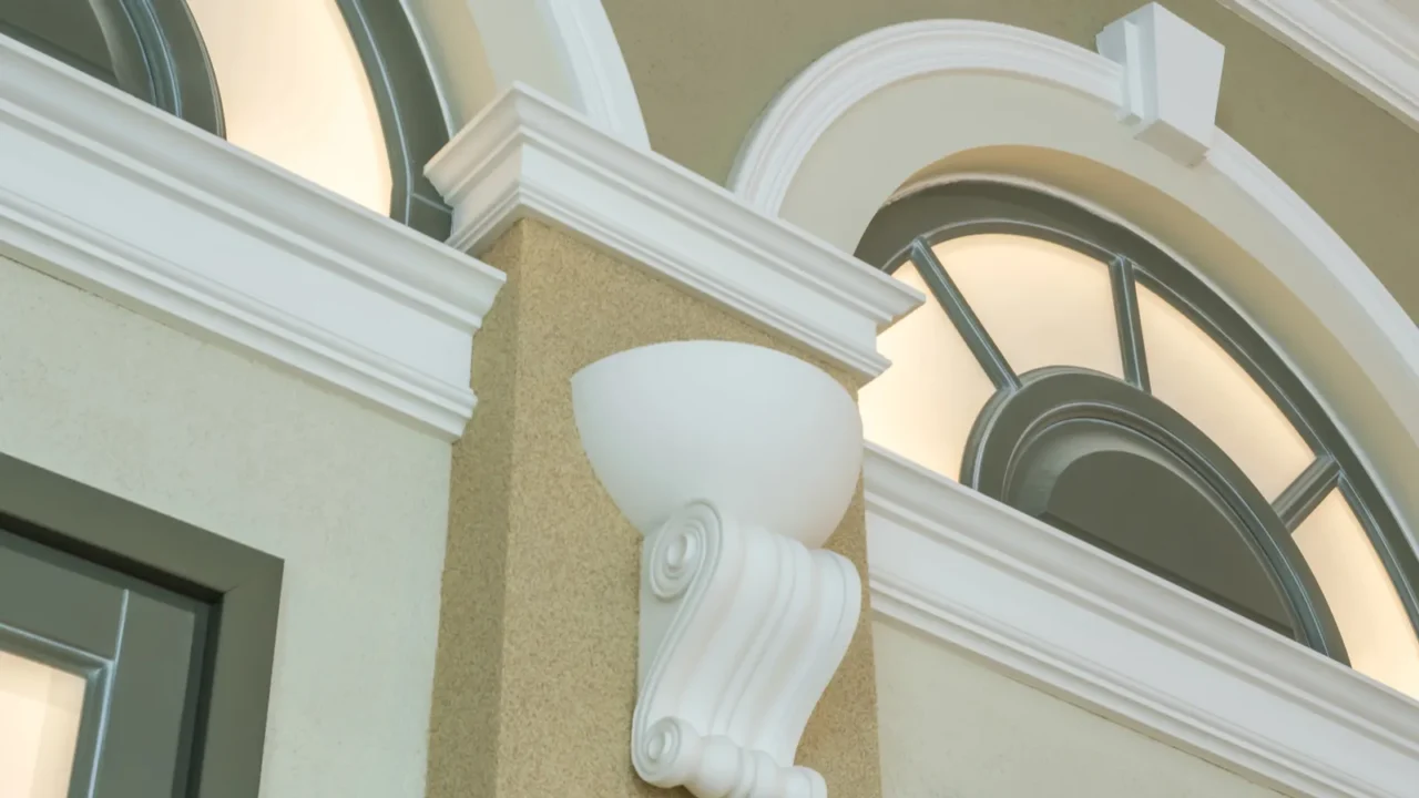 Architectural details including a white decorative element below a rounded light fixture, framed by smooth walls and arched windows above.