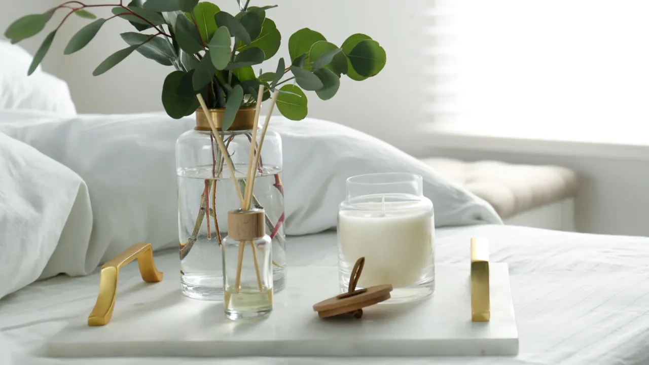 eucalyptus branches candle and aromatic reed air freshener on bed