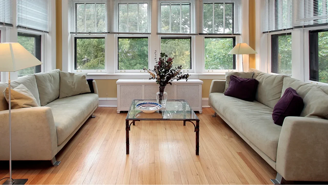 A cozy living room with two sofas, a coffee table with flowers, and large windows.