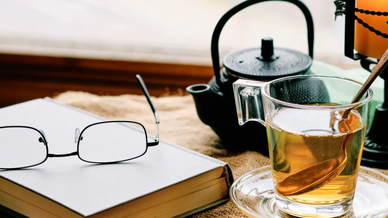 green tea cup book and candle on sackcloth by the