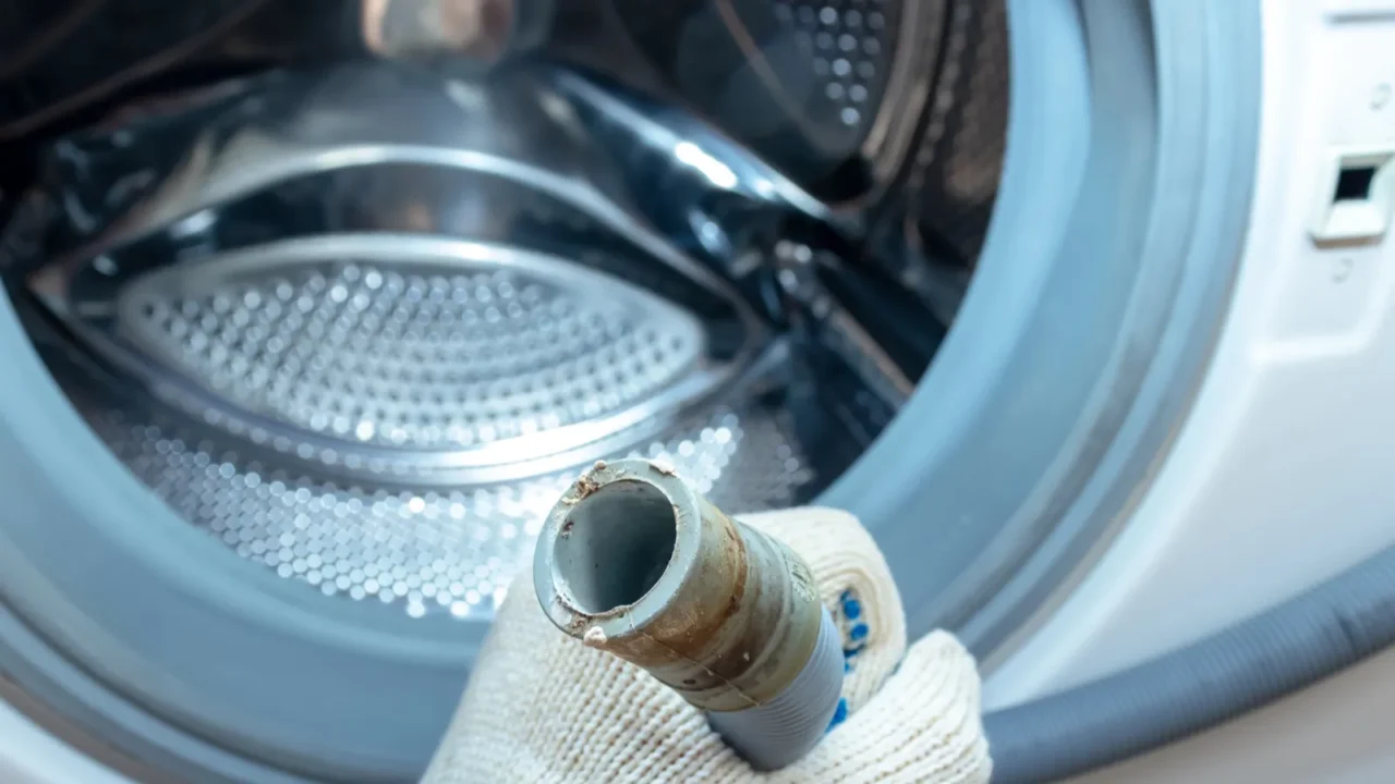 hand of a plumber holding a broken flexible drain hose