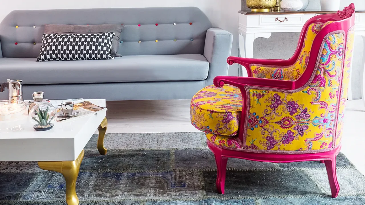 A colorful patterned chair next to a modern gray sofa and a chic coffee table.