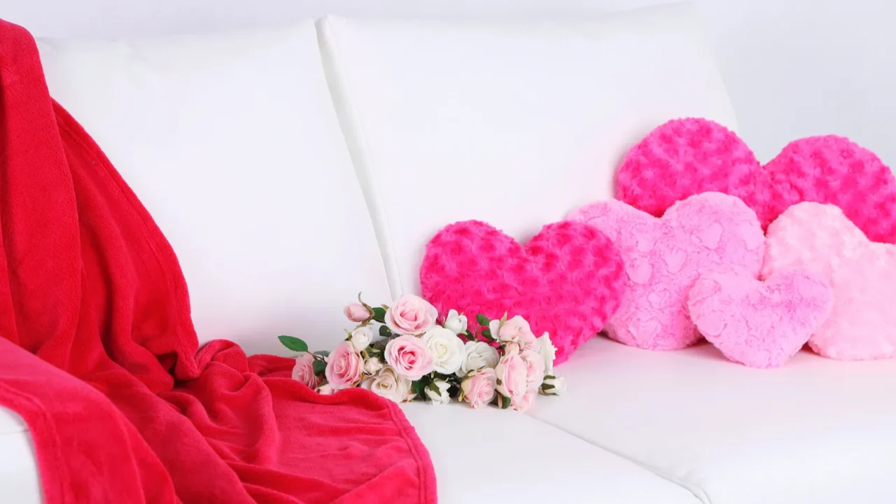 pink hearts shaped pillows and flowers on white sofa