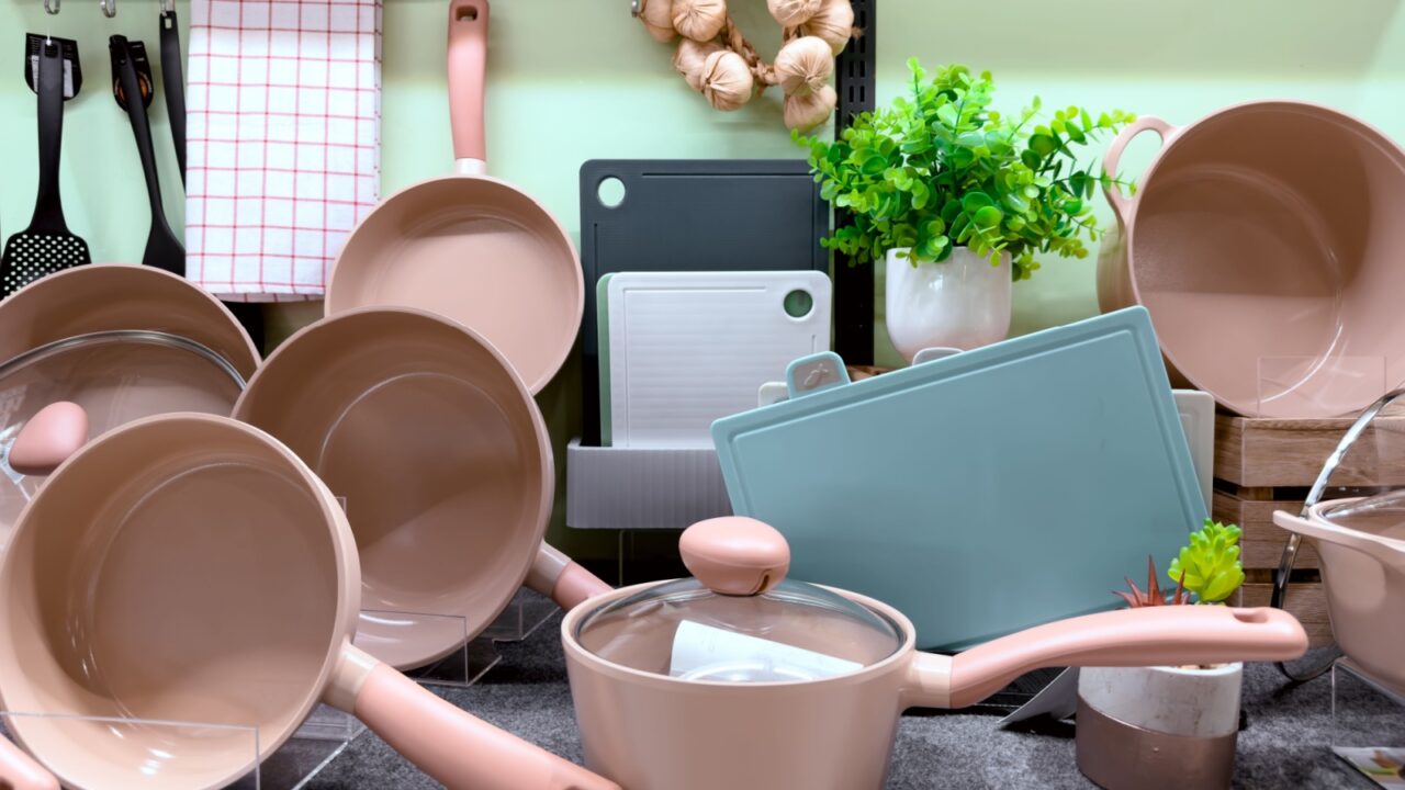 A collection of beige cooking pots and utensils arranged in a kitchen setting.