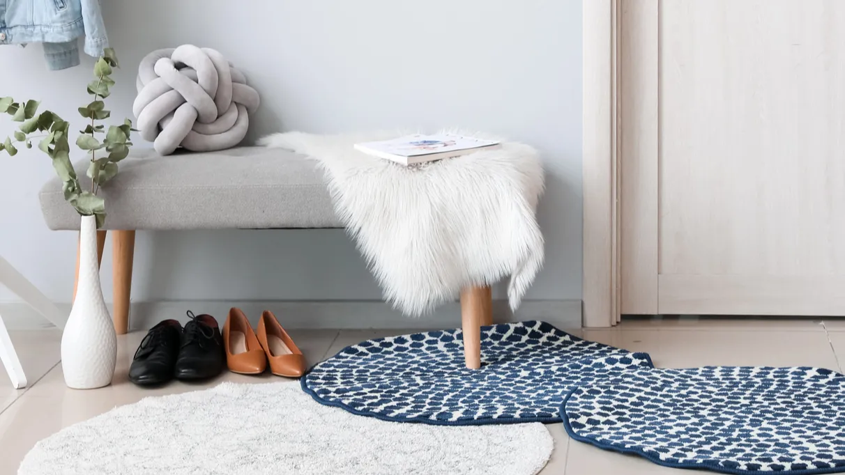 A cozy entryway with a gray bench, decorative items, and shoes on the floor.