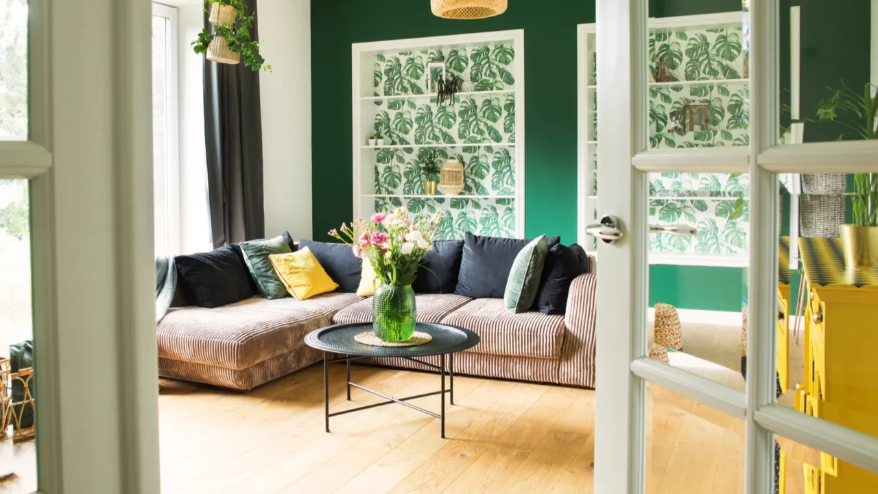 A cozy living room with a striped sofa, green walls, and a floral centerpiece.