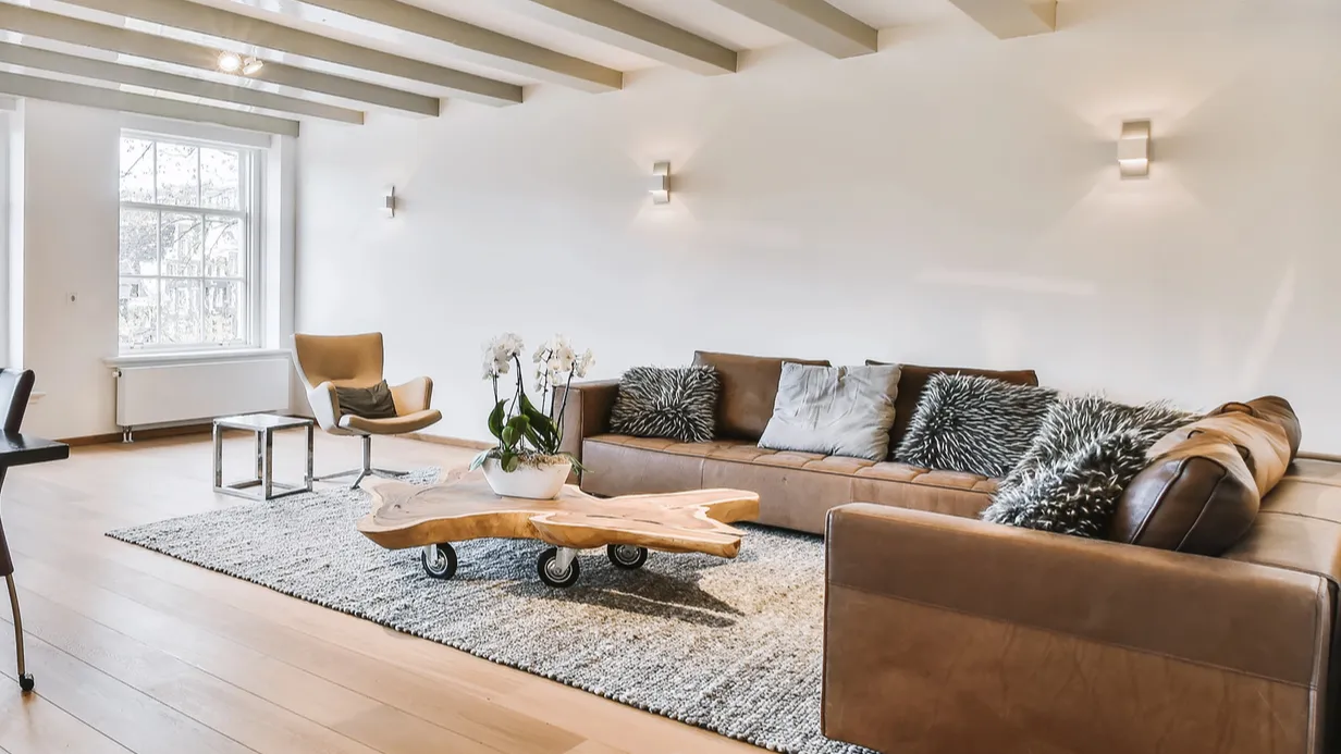 A modern living room with a brown couch and a rustic wooden coffee table.