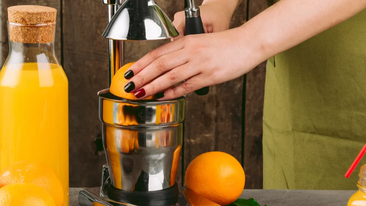 woman using orange juicer apparatus at home