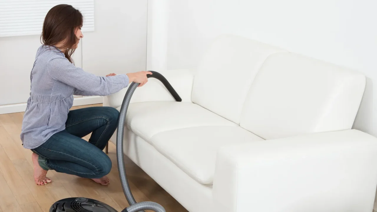 woman vacuuming sofa at home