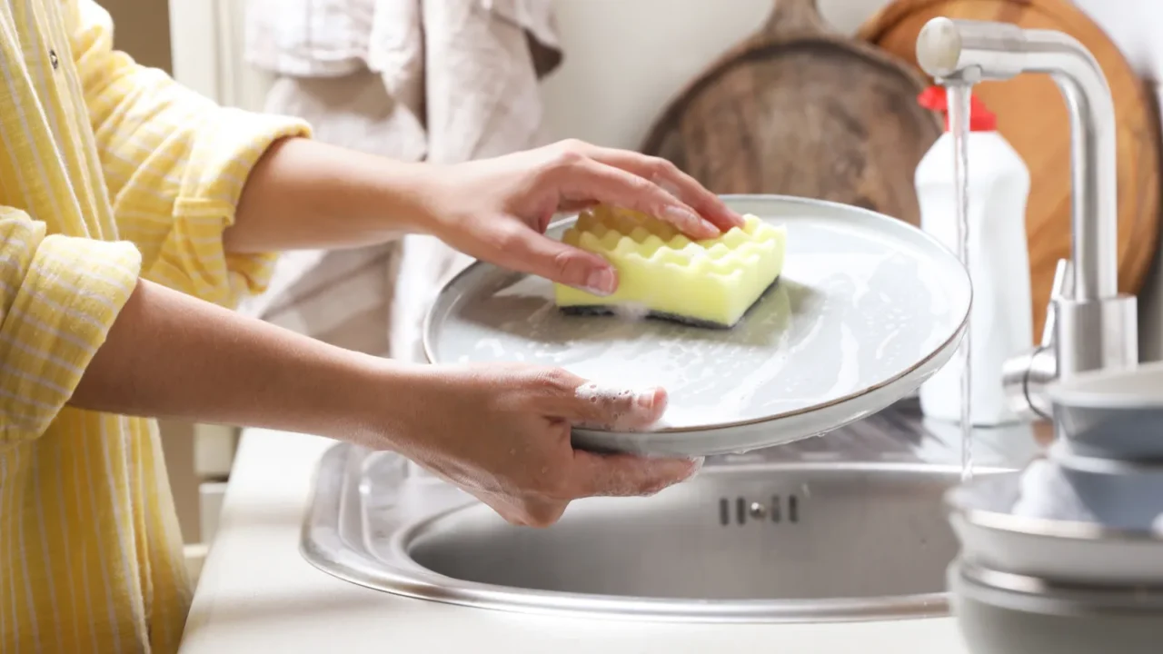 woman washing plate in kitchen sink closeup