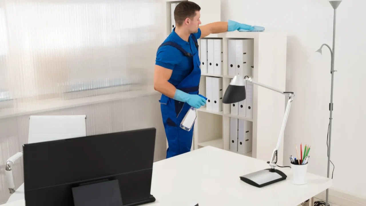 worker cleaning shelf at office