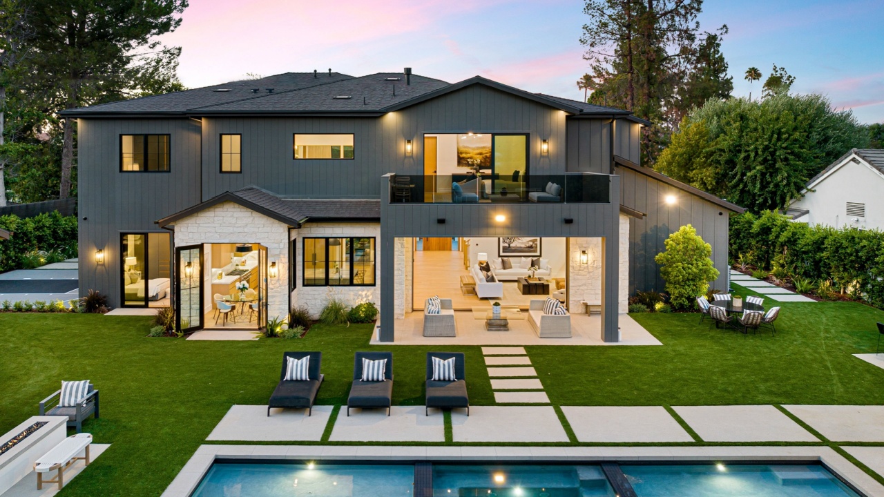 Modern luxury house with large backyard, swimming pool, and outdoor seating area at sunset.