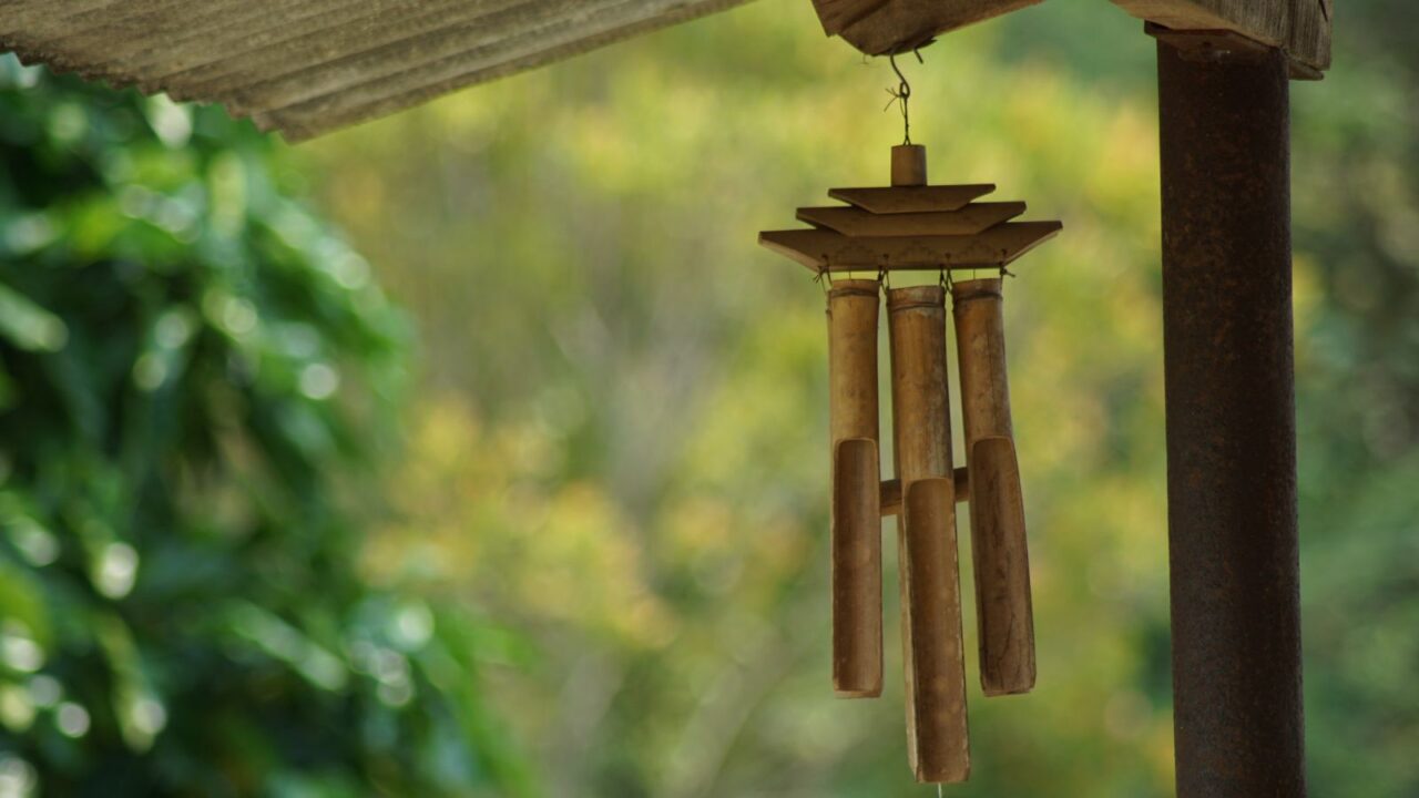 A bamboo wind chime hanging from the ceiling in a garden.