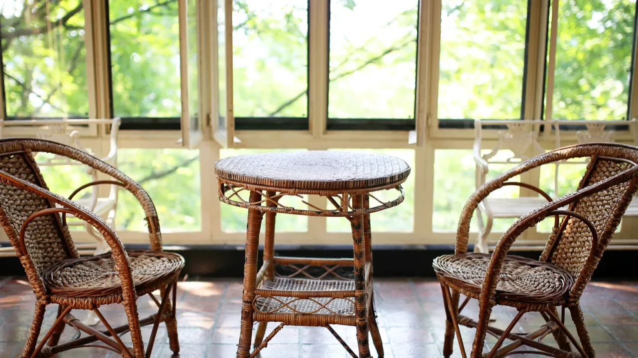 an old wicker bistro table and chair set sits empty