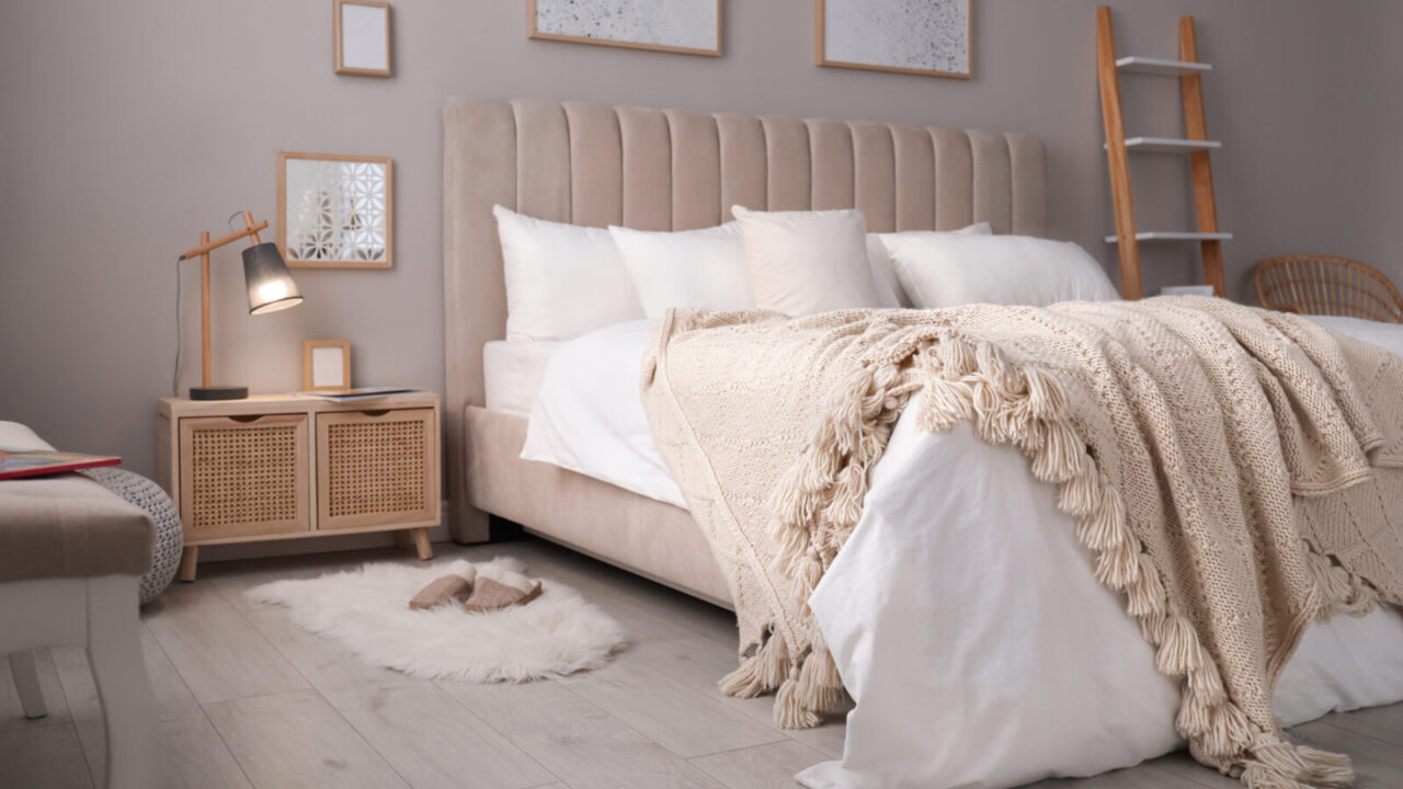 Cozy beige bed with textured blankets and stylish rattan nightstands.