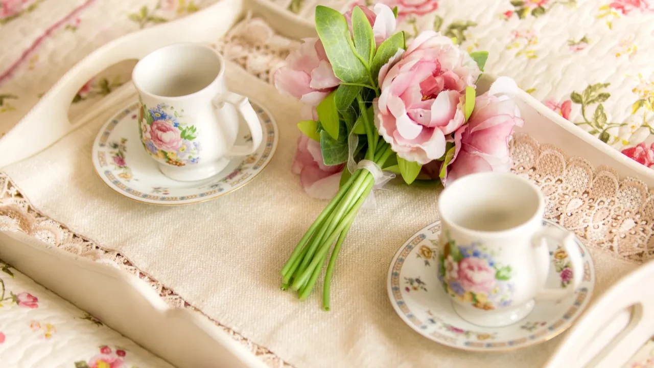 A floral tea set with pink flowers on a bedspread.