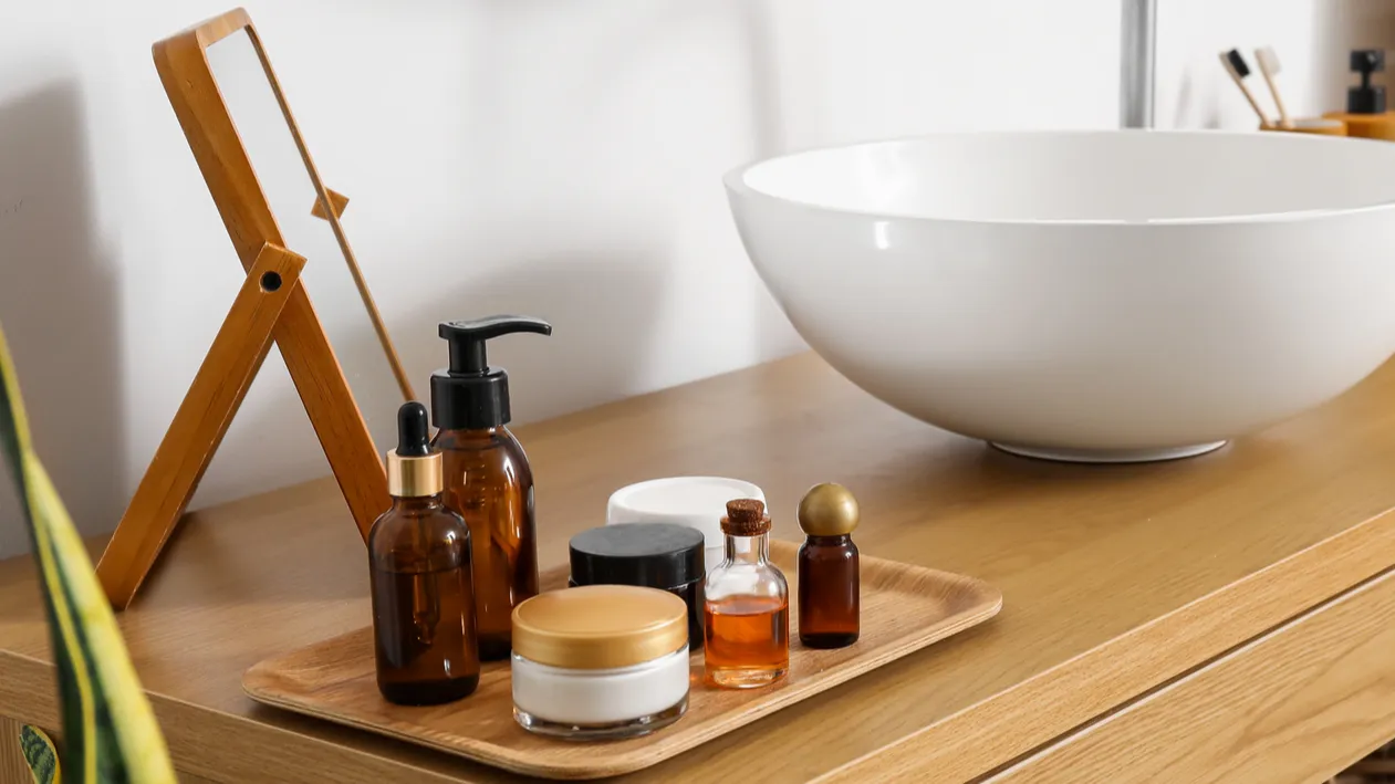 wooden table with sink and bath supplies near light wall